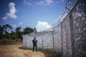 A border-guard stands next to a barbed wire fence on&nbsp;&hellip;