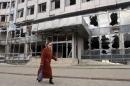 A woman walks past a building damaged by fighting in Donetsk