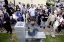 People gather around to sit and take photos during the unveiling of an Atheist monument outside the Bradford County Courthouse on Saturday, June 29, 2013 in Stark, Fla. The New Jersey-based group American Atheists unveiled the 1,500-bound granite bench Saturday as a counter to the religious monument in what's called a free speech zone. Group leaders say they believe it's the first such atheist monument on government property. About 200 people attended the event.(AP Photo/The Gainesville Sun, Matt Stamey)
