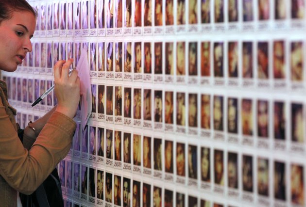 A single woman looks at bachelor's photos which are on display at the French dating site "adopt-a-guy" store in Paris
