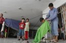 A Syrian refugee boy gets his hair cut as other refugees watch at a disused four-storey mall housing them in Deddeh village, northern Lebanon