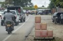 Motorists drive past containers of smuggled petrol placed along a roadside in Maicao, near La Guajira region