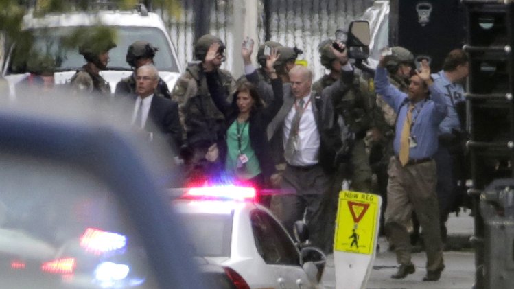 Evacuees raise their hands as they are escorted from the scene of a shooting at the Washington Navy Yard in Washington