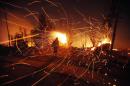 A person tries to extinguish flames as sparks fly during a forest fire in Valparaiso, Chile, early Sunday, April 13, 2014. Authorities say the fires have destroyed hundreds of homes, forced the evacuation of thousands and claimed the lives of at least seven people. (AP Photo/Luis Hidalgo)