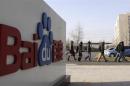 Employees walk past the logo of Baidu outside its headquarters in Beijing