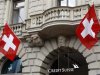 Switzerland national flags fly beside the logo of Swiss bank Credit Suisse at the company's headquarters in Zurich