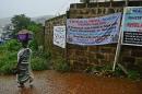 A woman walks past signs warning of Ebola in Freetown, an area which has been hit hard with the spread of the deadly virus, on August 13, 2014