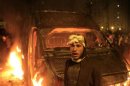A protester stands in front of a burning riot police vehicle after it was seized on the Kasr Elnile bridge in Cairo