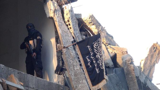 A fighter from the Al-Nusra Front poses next to the movement's flag in September 2014