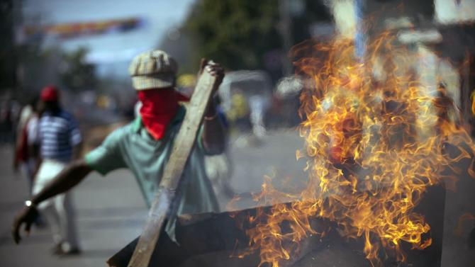 Protesters block a street with burning tires and barricades in the center of Port-au-Prince, on December 13, 2014