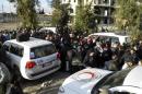 Civilians gather around vehicles as they wait to be evacuated from a besieged area of Homs
