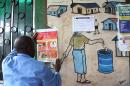 A nurse puts up an information sign about Ebola on a wall of a public health center on July 31, 2014 in Monrovia, Liberia