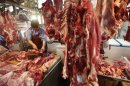 A butcher cuts up beef at a meat market in Beijing