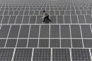 An employee walks on solar panels at a solar power plant in Aksu