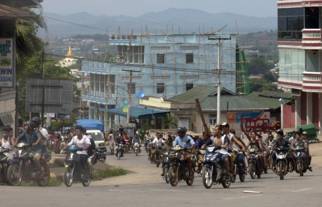 Hundreds of Buddhists on motorcycles armed with sticks patrol in the streets of in Lashio, northern Shan State, Myanmar, Wednesday, May 29, 2013. Sectarian violence spread to a new region of Myanmar, with a mob burning shops in the northeastern town after unconfirmed rumors spread that a Muslim man had set fire to a Buddhist woman. (AP Photo/Gemunu Amarasinghe)