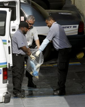 Miami-Dade morgue workers place objects in a bag outside …