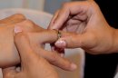 A bride places a wedding band on the finger of her soon-to-be husband during in Manila on February 14, 2013