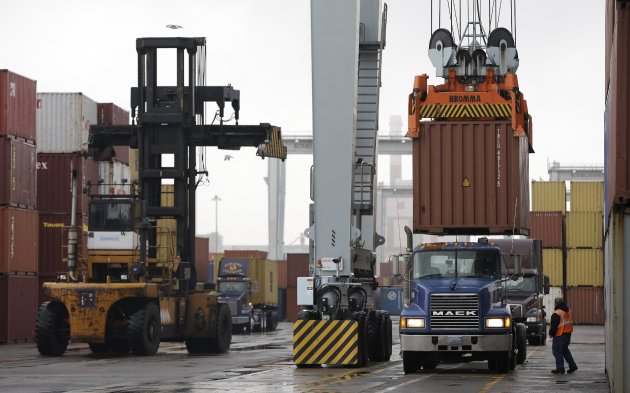 In this photo taken Tuesday, Dec. 18, 2012, a truck driver watches as a freight container, right, is lowered onto a tractor trailer truck by a container crane at the Port of Boston, in Boston. The crane and a reach stacker, left, are operated by longshoremen at the port. The longshoremen's union may strike if they are unable to reach an agreement on their contract that expires Dec. 29, 2012. (AP Photo/Steven Senne)