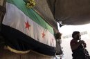 Free Syrian Army fighters hold their weapons while standing near an opposition flag at their post in Aleppo's Bustan al-Qasr