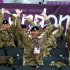 British Army soldiers perform a "Mexican Wave" as they watch men's beach volleyball