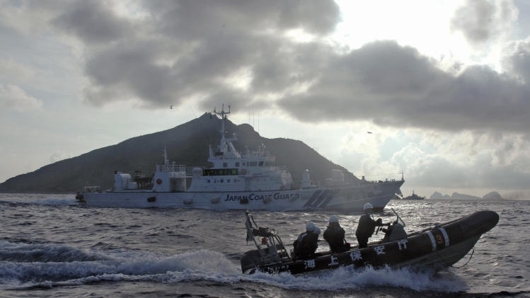 Japanese Coast Guard boat and vessel sail alongside Japanese activists' fishing boat, not in photo, warning the activists away from a group of disputed islands called Diaoyu by China and Senkaku by Japan, early Sunday, Aug. 18, 2013. Nearly two dozen Japanese nationalist activists and fishermen have sailed to a small group of islands at the center of a territorial dispute with China. They were closely monitored by Japan’s Coast Guard, but there were no Chinese patrols in the area and no incidents were reported. (AP Photo/Emily Wang)