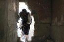 A Free Syrian Army fighter moves through a hole in a wall in the Bab al-Nasr neighborhood of Aleppo