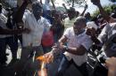 A man yells out in pain as his hand catches fire from a burning Dominican national flag he was holding, during an anti-Dominican Republic protest, in front of the country's consulate in Port-au-Prince, Haiti, Wednesday, Feb. 25, 2015. Protesters outraged over a Feb. 11 lynching of young man of Haitian descent in the Dominican city of Santiago are demanding that the neighboring country respect the human rights of Haitians. (AP Photo/Dieu Nalio Chery)