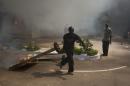 Anti-government protestor carries a burning object outside the parliament building in Ouagadougou