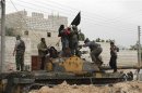 Members of the Free Syrian Army raise a black flag over a tank that belonged to pro-government forces in Salqin city in Idlib