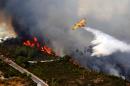 A seaplane drops water over a wildfire next to a residential area along the coast near the Spanish resort of Javea, on September 5, 2016