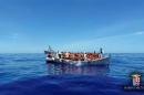 Migrants sit in their boat during a rescue operation by Italian navy ship Grecale off the coast of Sicily