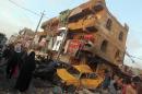 Iraqis inspect the scene of a car bomb attack in the mostly Shiite Sadr City district on December 5, 2014