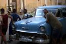 Pedestrians lean against an American classic car as they wait for traffic to pass in Old Havana, Cuba, Tuesday, Feb. 17, 2015. A more relaxed and hopeful atmosphere is evident in Cuba as a result of President Raul Castro's modest reforms and after the agreement by Cuba and the U.S. to move toward a more normal relationship. (AP Photo/Ramon Espinosa)