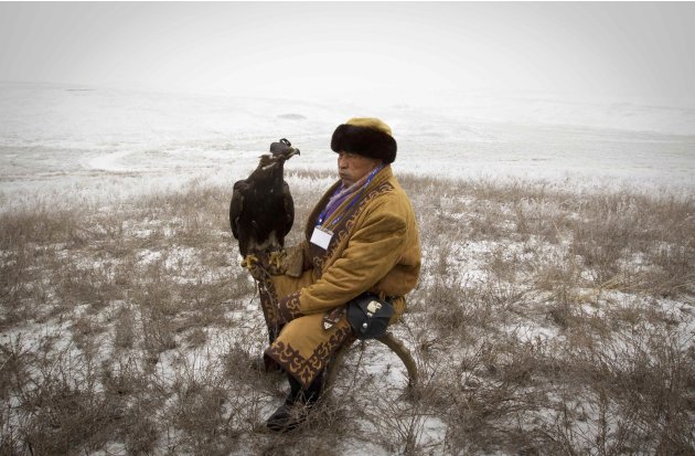 A hunter rests with his tame golden eagle during an annual hunting competition outside Almaty
