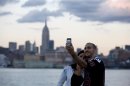 With the skyline of New York behind them, a couple takes a picture of themselves from a pier in Hoboken