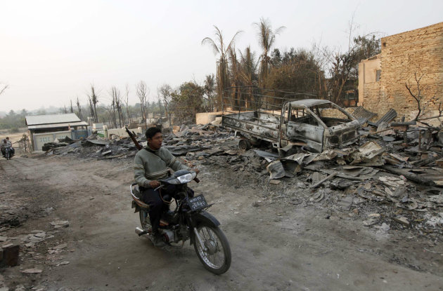 A Myanmar police officer rides a motorbike past debris of buildings and a truck destroyed during ethnic unrest between Buddhists and Muslim, as he provides security in Meikhtila, about 550 kilometers (340 miles) north of Yangon, Myanmar, Monday, March 25, 2013. Sectarian clashes between Buddhists and Muslims in Myanmar spread to at least two other towns in the country's heartland over the weekend, undermining government efforts to quash an eruption of violence that has killed dozens of people and displaced 10,000 more. On Sunday, Vijay Nambiar, the U.N. secretary-general's special adviser on Myanmar, toured Meikhtila, where soldiers were able to impose order after several days of anarchy, and called on the government to punish those responsible. (AP Photo/Khin Maung Win)