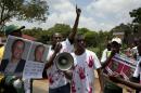 Members of the Rwanda National Congress opposition party shout slogans while holding pictures of slain party founder Patrick Karegeya (L) outside the Rwandan embassy in Pretoria on January 9, 2014