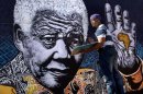 FILE - In this Monday, July 15, 2013 file photo, South African artist John Adams works on a giant acrylic-on-canvas painting of Nelson Mandela in the driveway of his house in a suburb of Johannesburg, South Africa. Many South African artists and graphic designers are celebrating Nelson Mandela's 95th birthday who remains hospitalized as hit condition improves Thursday July 18, 2013.(AP Photo/Ben Curtis, File)