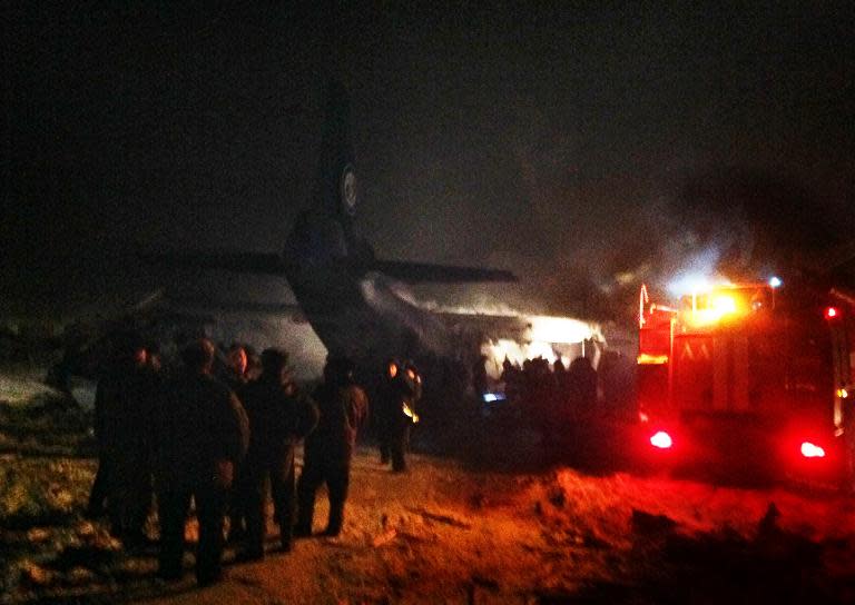A picture taken on December 26, 2013 and released by Russia’s Emergencies Ministry shows firefighters and recuers working near an Antonov An-12 military transport plane which crashed near the Siberian city of Irkutsk