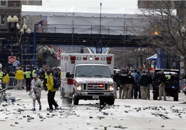 A runner is escorted from the scene after explosions went off at the 117th Boston Marathon in Boston