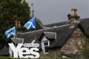 Scottish flags fly above a sign in support of the Yes campaign outside a house in Pitlochry , Scotland