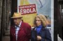 People walk past an advert calling for financial help to fight Ebola in Africa on Friday, Oct. 10, 2014 in Madrid downtown, Spain. A Spanish hospital official says the nursing assistant Teresa Romero, infected with Ebola, is "stable," hours after authorities described her condition as critical. Romero is the first person known to have caught the disease outside the outbreak zone in West Africa, contracting the virus while helping treat a Spanish missionary who became infected in West Africa, and later died. (AP Photo/Santi Palacios)