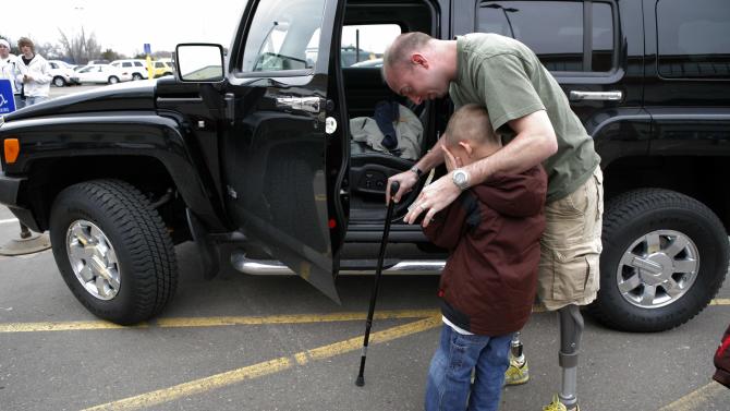 FILE - In this April 7, 2008 file photo, retired Minnesota National Guard Sgt. John Kriesel comforts his son, Broden, 5, outside a mall in Roseville, Minn.Kriesel lost both of his legs in a roadside bomb attack while patrolling near Fallujah, Iraq in December 2006. Veterans of the Iraq War watched in frustration as Republican presidential contenders have distanced themselves from the original decision their party enthusiastically supported to invade that country. Some veterans say they long ago concluded their sacrifice was in vain, and are annoyed that a party that fervently lobbied for the war is now running from it. Other say they still believe their mission was vital, regardless of what the politicians say. And some find the gotcha question being posed to the politicians _ knowing what we know now, would you have invaded? _ an insult in itself. (AP Photo/Jae C. Hong, File)