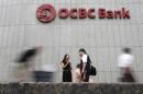 Office workers pass a logo of Overseas-Chinese Banking Corp Ltd (OCBC) at the company's headquarters in Singapore
