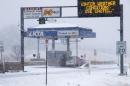 An SUV goes through a toll booth on the Kansas Turnpike during a winter storm, Tuesday, Feb. 4, 2014, near Lecompton, Kan. The storm has left the turnpike and other major highways in Kansas packed with snow. (AP Photo/John Hanna)