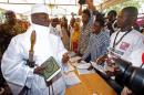 Gambian President Jammeh holds a copy of the Quran while speaking to a poll worker at a polling station during the presidential election in Banjul