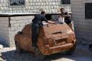 Rebel fighters cover a car in mud for camouflage at an undisclosed location in Syria's northwestern province of Idlib on October 8, 2013