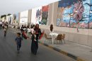 In this Tuesday, Oct. 23, 2012 photo, a Libyan family in Tripoli walk by a mural exhibition celebrating one year since the fall of dictator Muammar Gadhafi in Tripoli, Libya. One year on, the country is still trying to overcome the legacy of one of the most erratic leaders of modern times as well as a brutal eight month struggle that left the country awash in weapons, militias and very few viable institutions of the state. (AP/Paul Schemm)