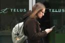 A woman uses a mobile device while walking past a Telus store in Ottawa