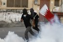 Anti-government protesters, one of them holding a Bahraini flag, run to take cover from tear gas in the village of Sanabis